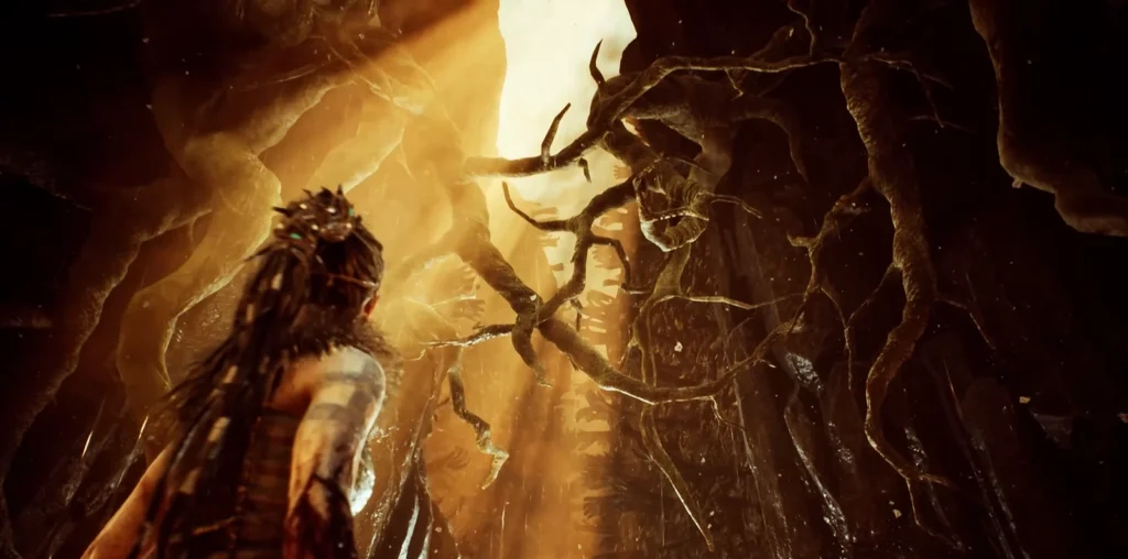 Senua faces twisted roots inside glowing cave in Hellblade