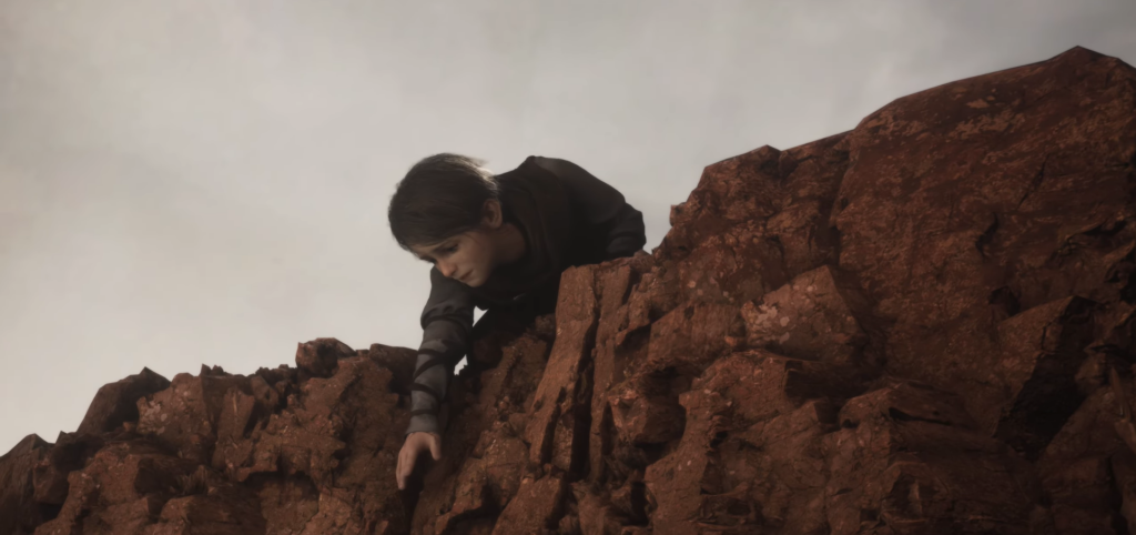 Young boy climbing red rocky cliff.