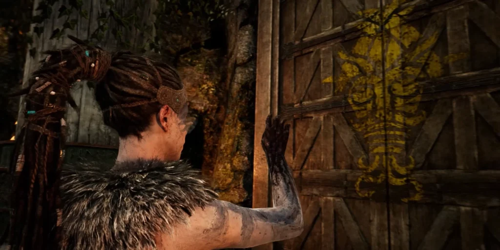 Senua from Hellblade touches wooden door with yellow symbol