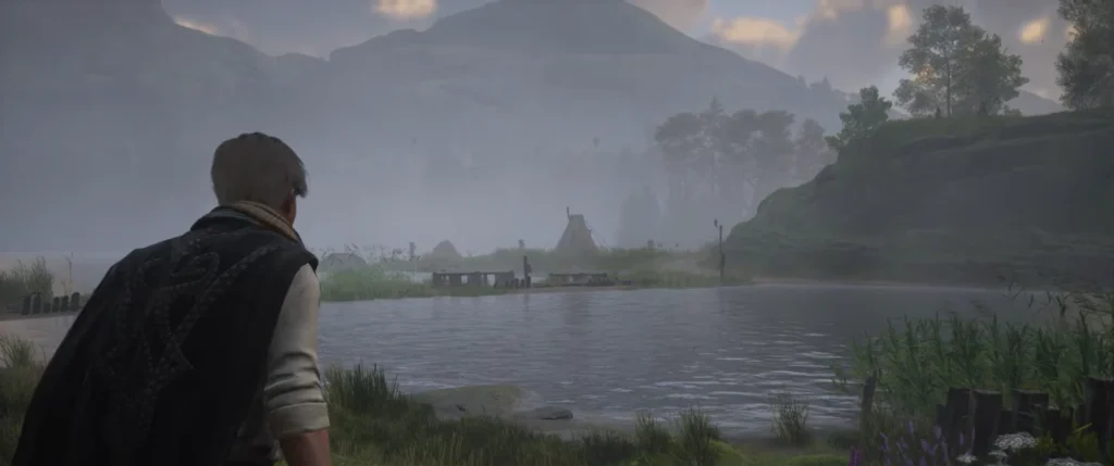 Man looking across misty lake near mountains