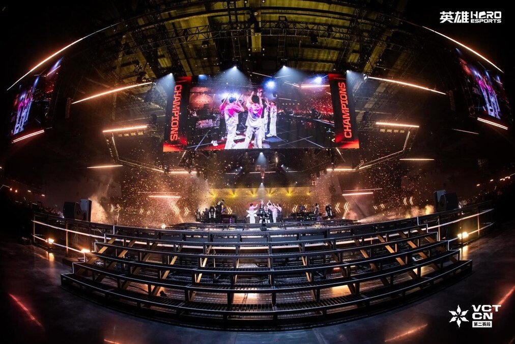 Esports team celebrates on stage under arena screens