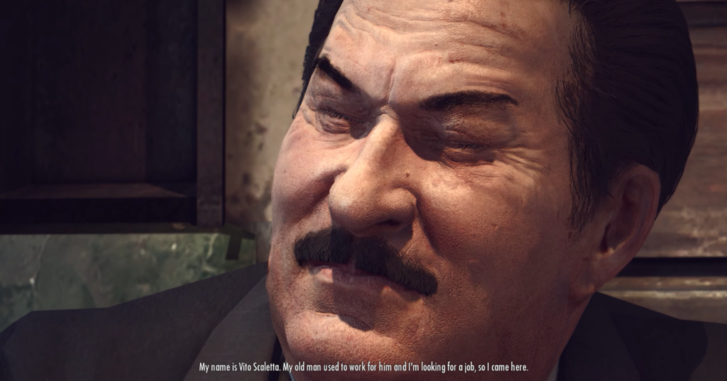 Man with mustache speaking, serious expression.