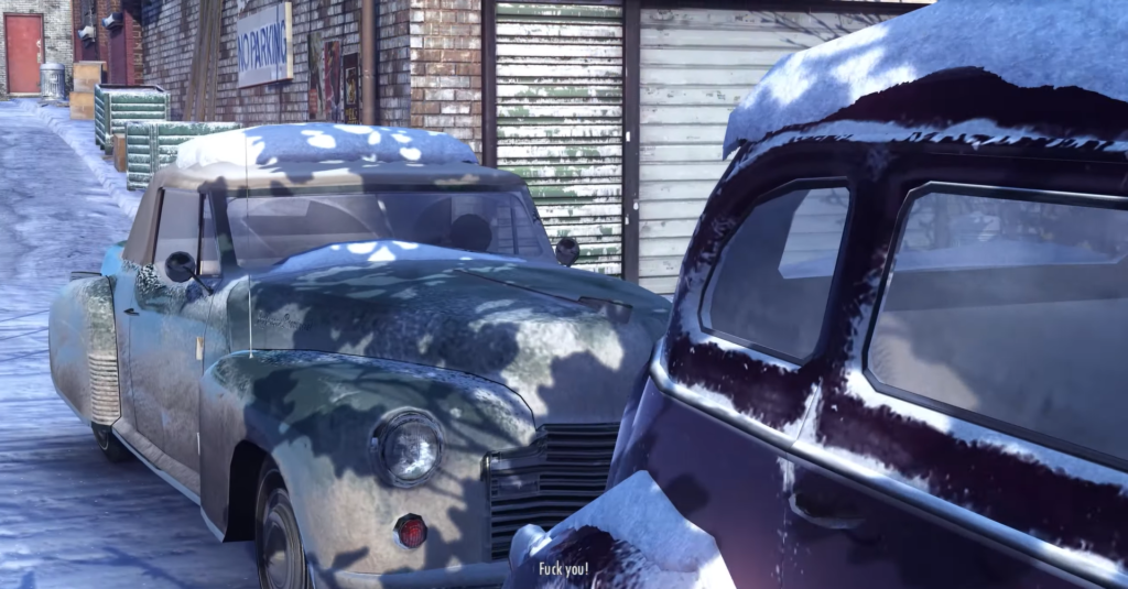 Snow-covered vintage cars in alley.