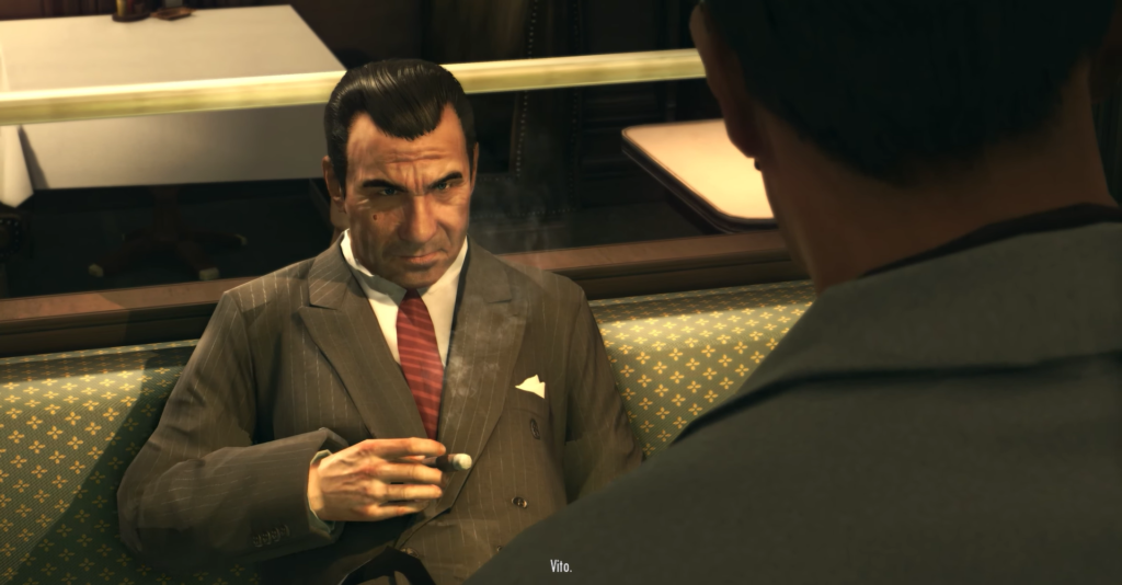 Man in suit smoking, seated, talking.