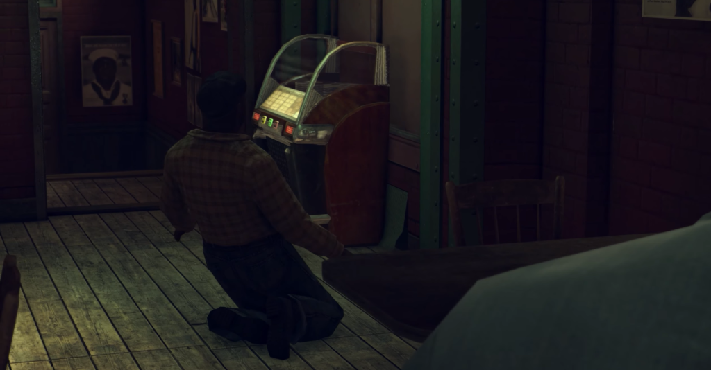 Man kneeling near vintage jukebox.
