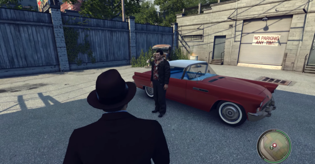 Man in suit stands near red convertible.