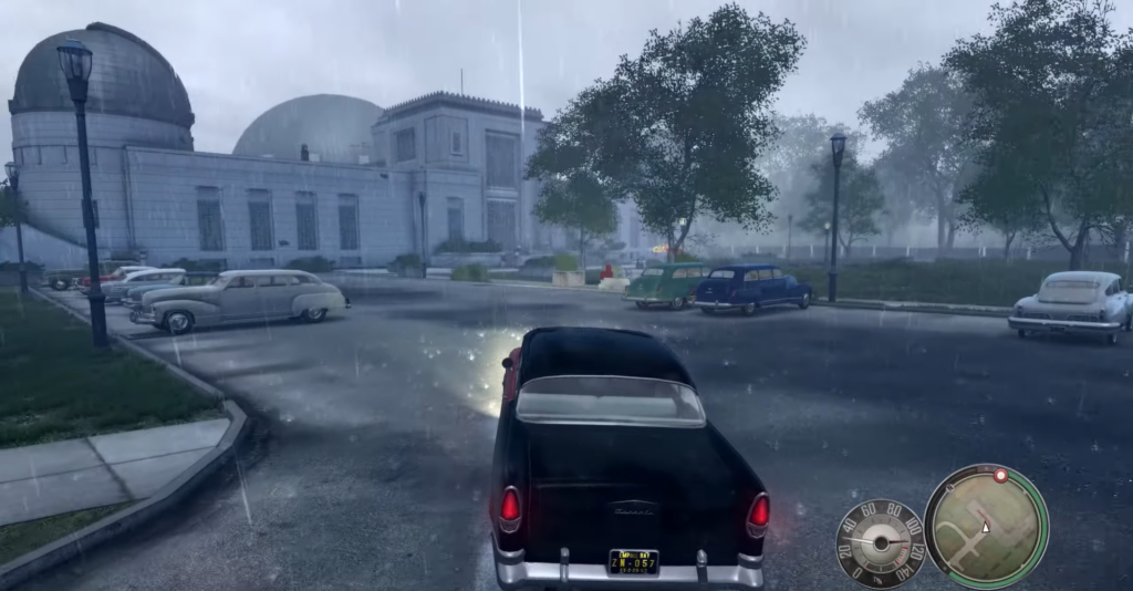 Black car driving in rainy street.