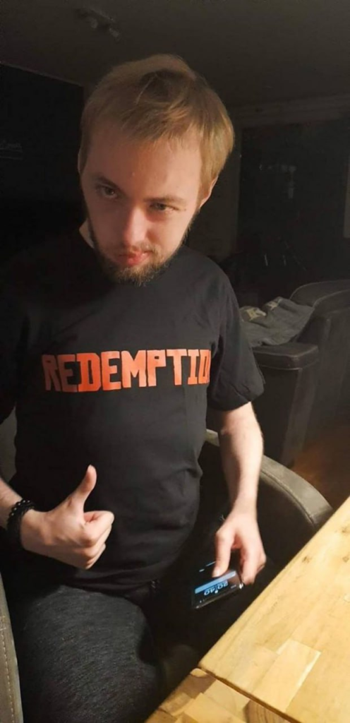 Man wearing black "REDEMPTION" shirt, thumbs up.