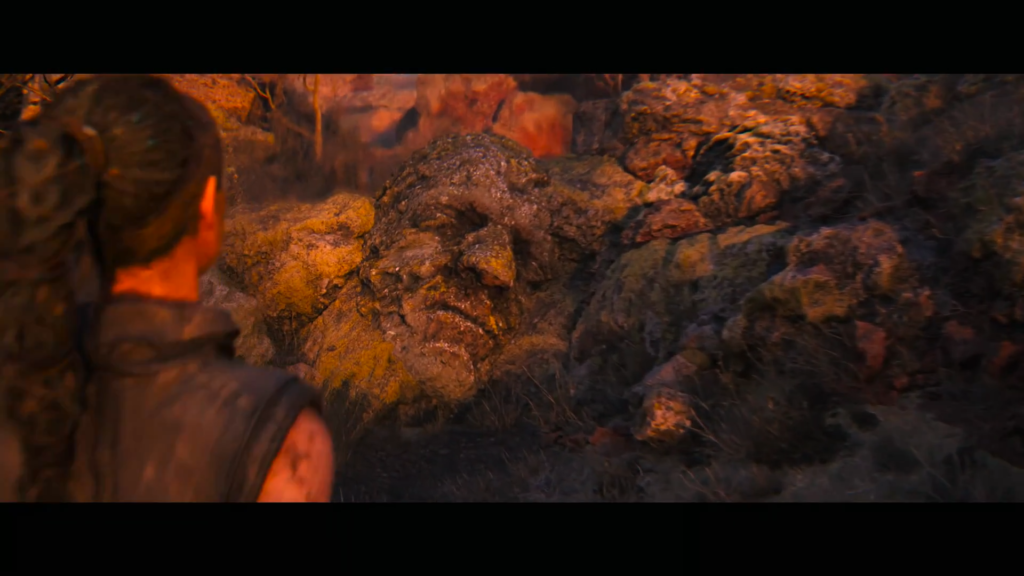 Woman looks at giant stone face in rocky landscape