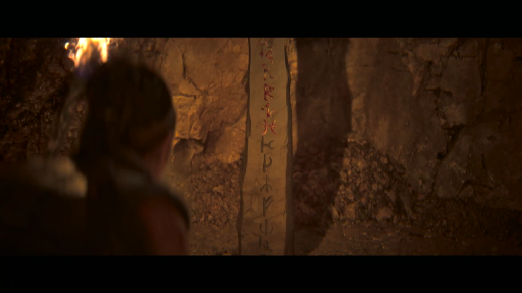 Person examines rune-carved stone pillar in cave