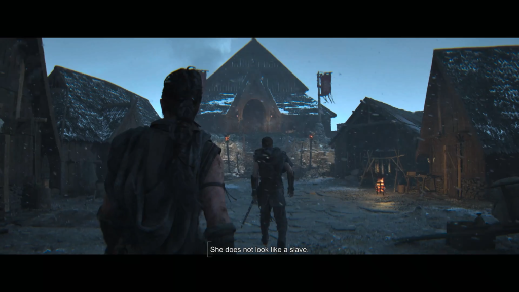 Two warriors walk through snowy village toward hall