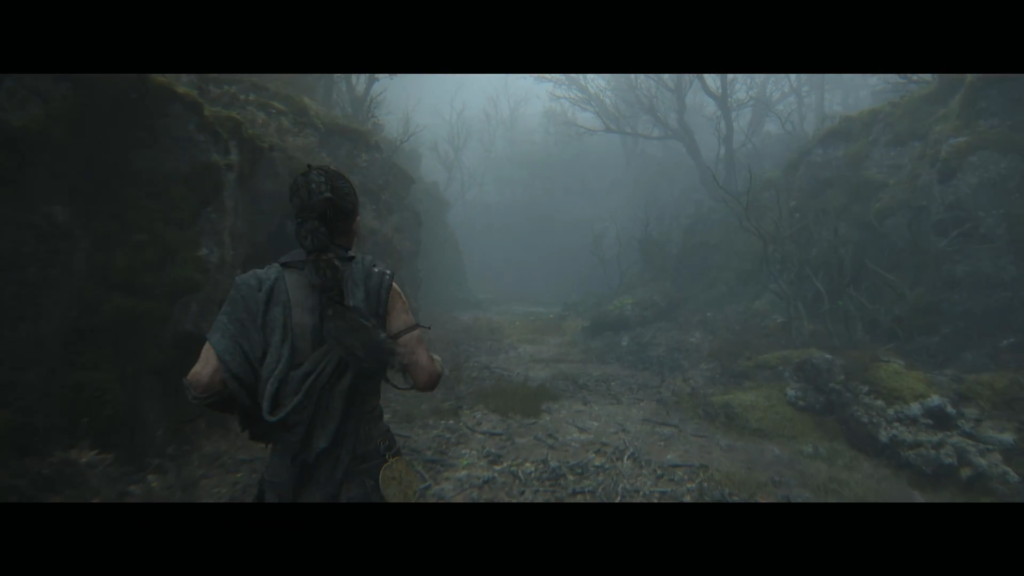 Woman walking along foggy forest path between rocky walls