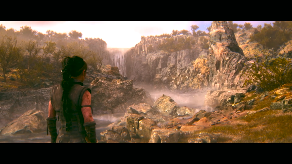 Woman looks at waterfall in rocky canyon landscape