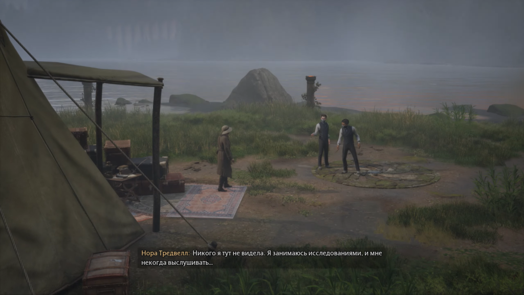 Three people talk at lakeside campsite near tent