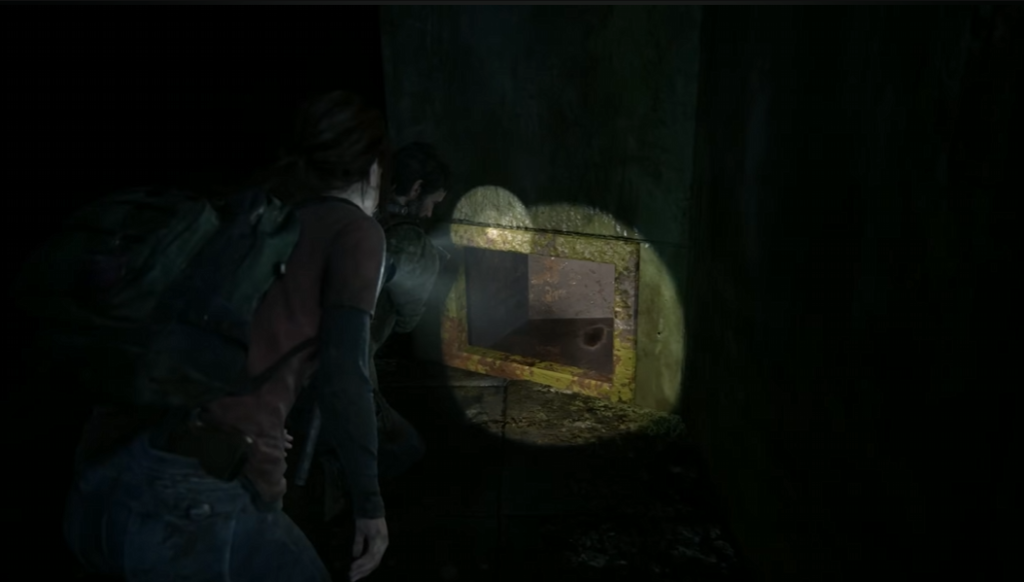 Ellie and Joel aim flashlight at wall safe in The Last of Us