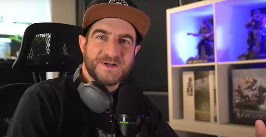Man wearing cap speaks into microphone at desk