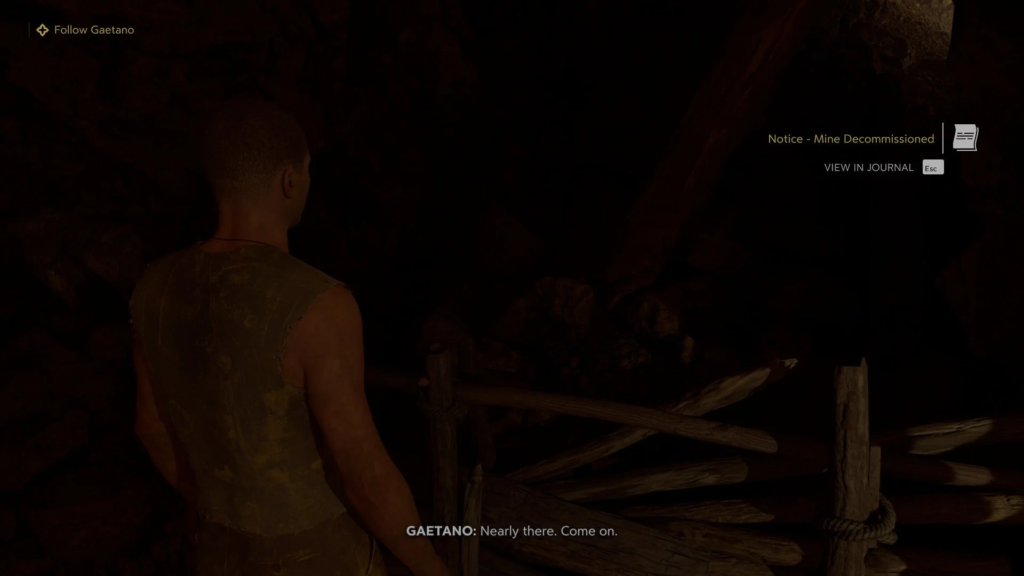 Gaetano stands in dark mine tunnel near wooden barrier