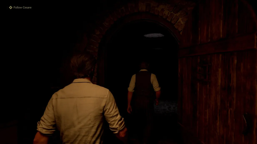 Man following Cesare through dark stone archway doorway
