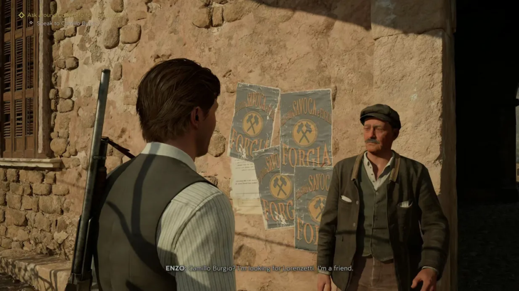 Enzo talks to man beside posters on wall