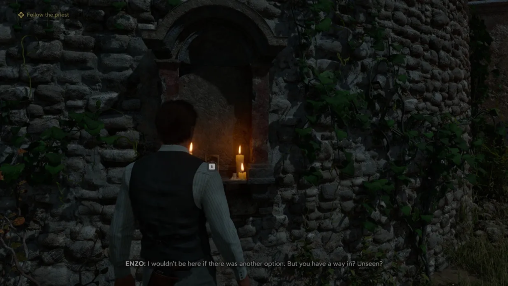 Man facing candles in stone wall alcove outdoors