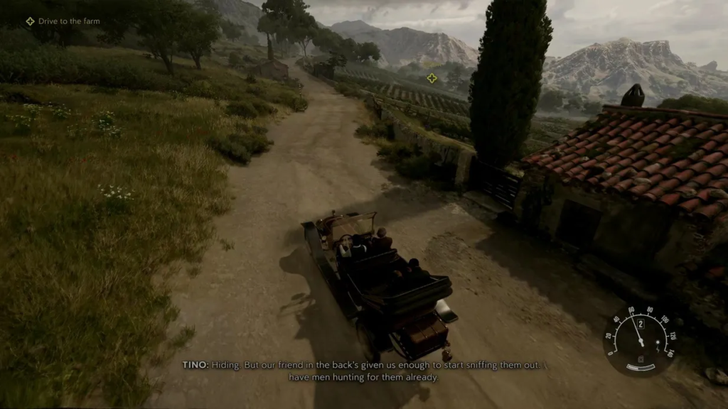 Car driving on dirt road past farmhouse and mountains