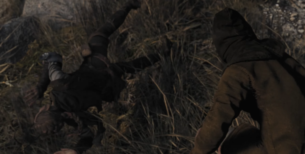 Two hooded figures crawling through tall grass outdoors