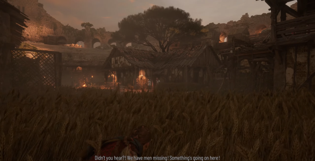 Person crouching in wheat field near village ruins