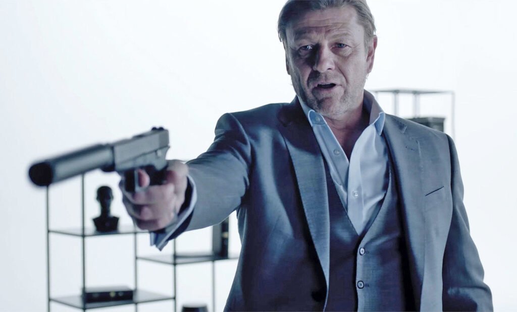 Man in gray suit aiming pistol indoors