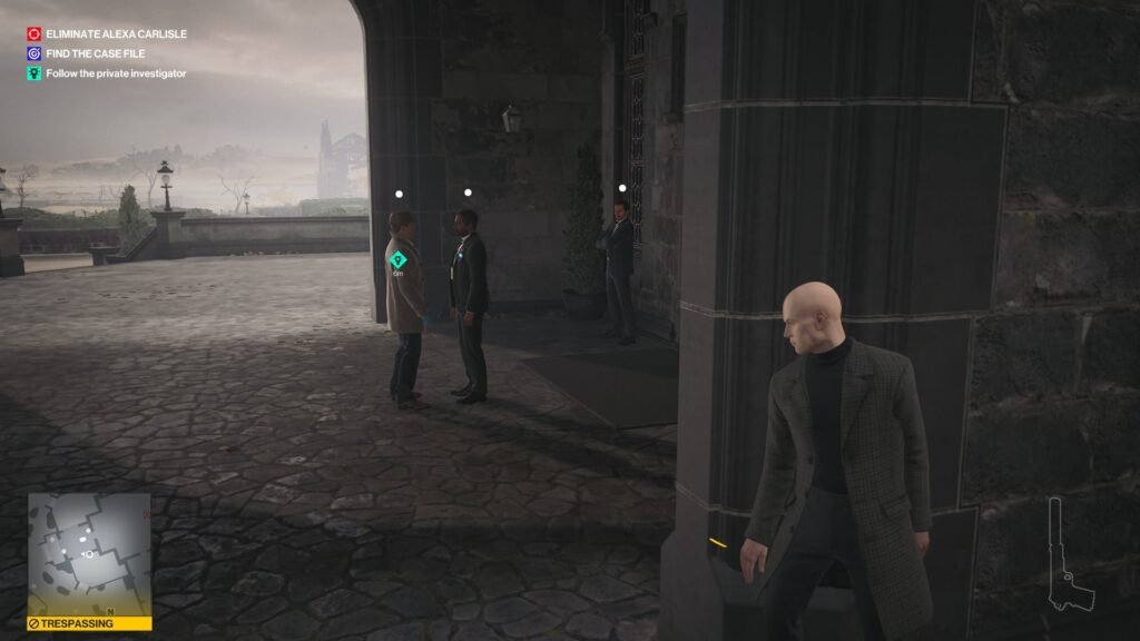 Agent 47 hides behind pillar outside stone building