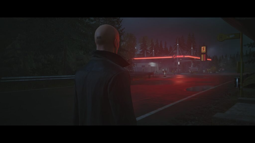 Agent 47 watches red-lit gas station at night