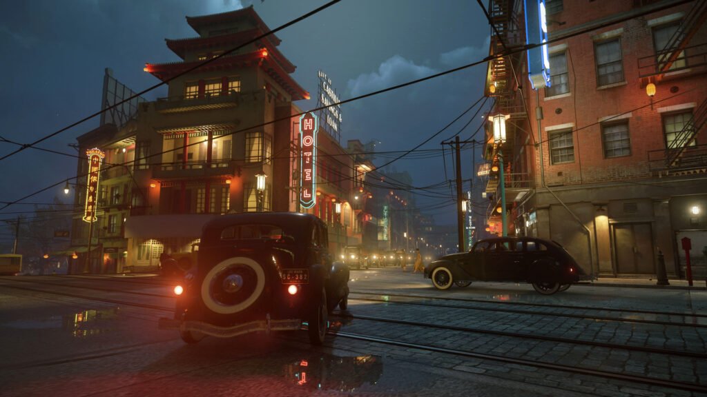 Vintage cars driving past neon hotel at night