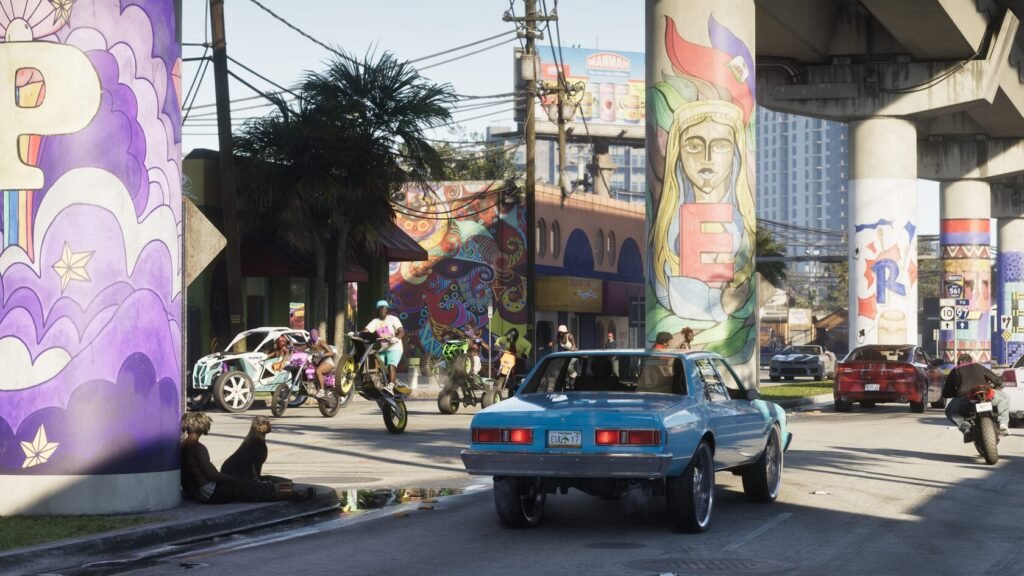 Blue car driving past graffiti under highway overpass